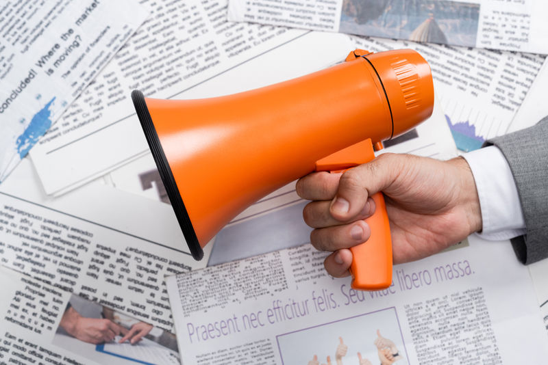 top-view-of-man-holding-megaphone-above-newspapers-2023-11-27-04-55-40-utc.jpg